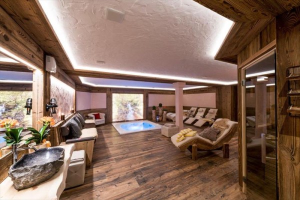 Luxusní wellness prostor s vířivkou a lehátky na dřevěné podlaze.