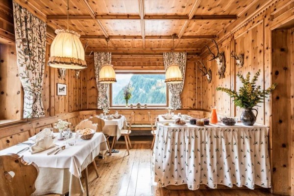 Dřevěná horská restaurace s prostřenými stoly, dekoracemi a výhledem na hory.