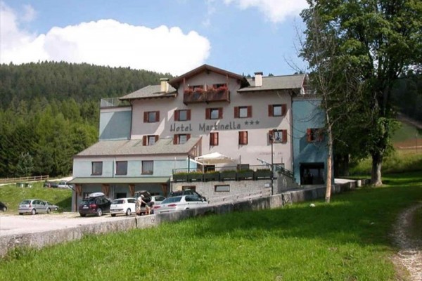 Hotel v horské krajině s parkovištěm před ním.  