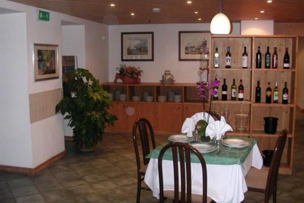 Elegantně prostřený stůl v restauraci s dřevěným obložením a regálem s lahvemi vína.