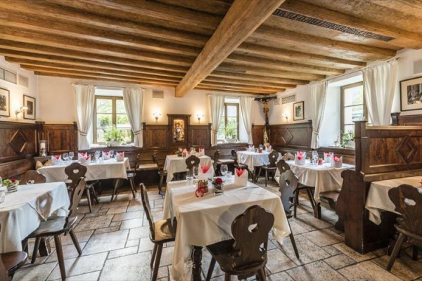 Interiér restaurace se dřevěnými stoly a židlemi, prostřený bílým ubrusem.