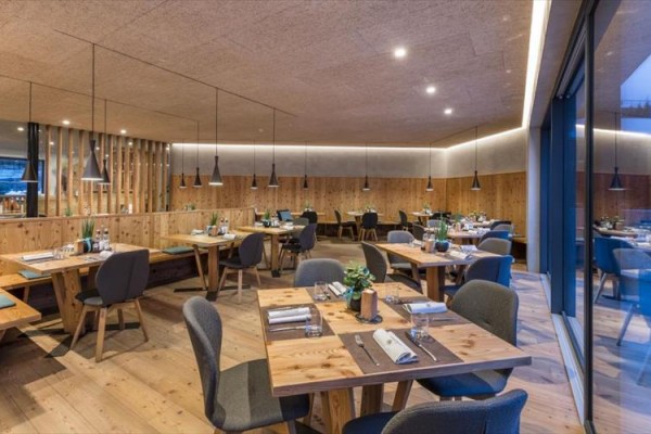 Moderní restaurace s dřevěným nábytkem a šedými židlemi.