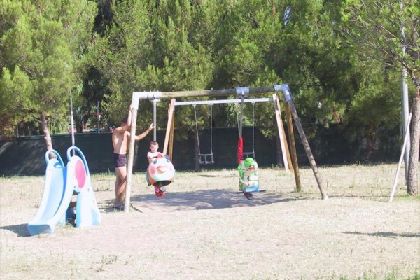 Struktura houpaček a skluzavka na dětském hřišti s dospělým a dítětem.