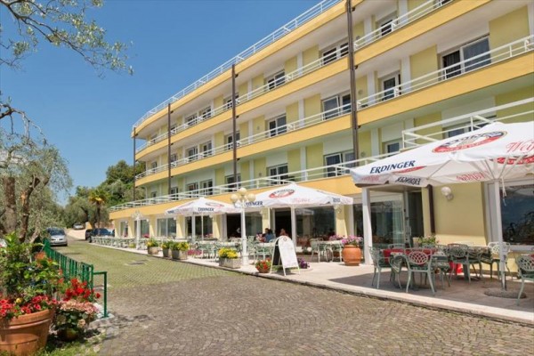 Podél třípatrového hotelu se stolky a slunečníky na terase.