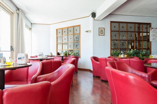 Restaurace s červenými křesly a dřevěnou podlahou.