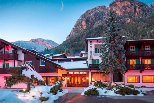 Hotel obklopený zasněženými horami a stromy při soumraku.