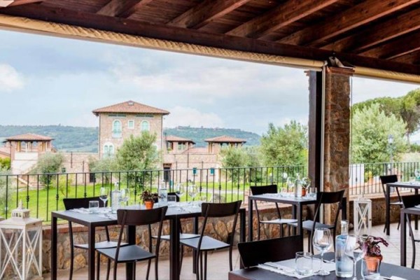 Restaurace s venkovním posezením a výhledem na krajinu s domy.