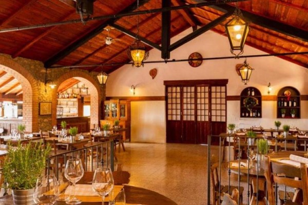 Interiér rustikální restaurace s dřevěnými trámy a prostřenými stoly.