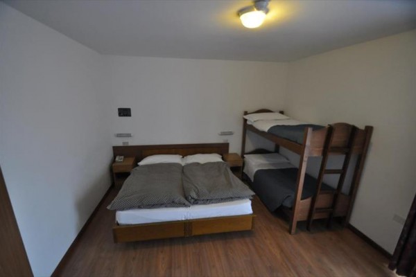 Ložnice se dvěma postelemi a palandou pod stropním světlem.