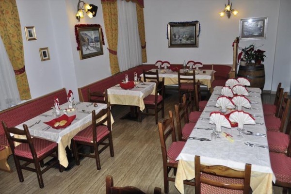 Restaurace s připravenými stoly, červeným čalouněním a žlutými ubrusy.  