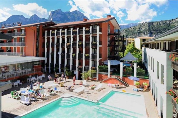 Hotel s venkovním bazénem a horami v pozadí.