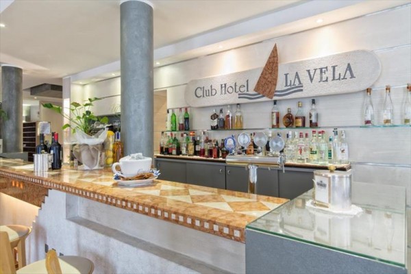 Barový pult s lahvemi alkoholu v hotelu Club Hotel La Vela.  