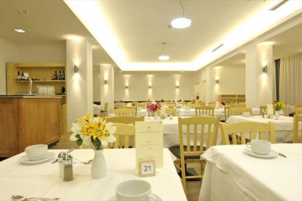 Elegantní restaurace s dřevěnými židlemi a ubrusy, s květinami na stolech.
