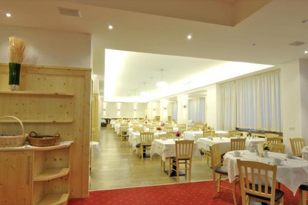 Světlá restaurace s prostřenými stoly a dřevěnými židlemi.