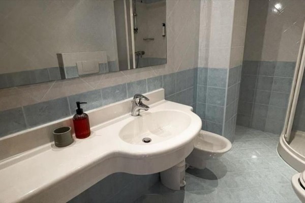 Moderní koupelna s umyvadlem, sprchovým koutem a zrcadlem.