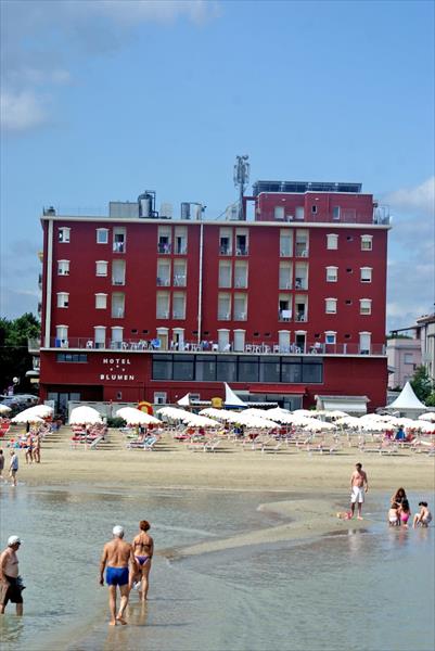 Hotel u pláže s lidmi procházejícími mělčinou.
