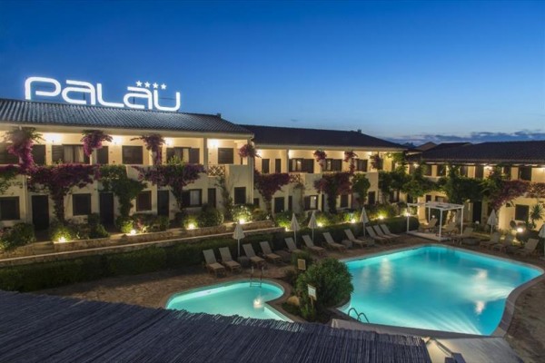 Hotel Palau s bazénem a večerním osvětlením.