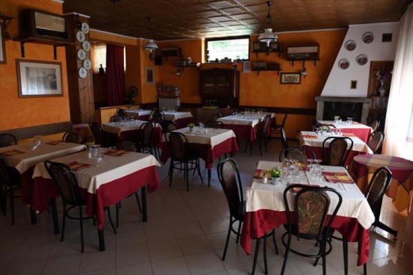 Restaurace s oranžovými stěnami, prostřenými stoly a dřevěnými židlemi.