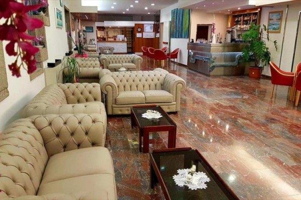 Elegantní hotelová lobby s béžovými pohovkami a dřevěnými konferenčními stolky.