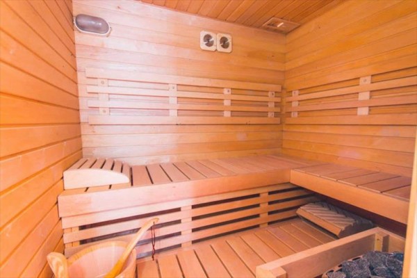 Dřevěná sauna s lavicemi a vědry na vodu.