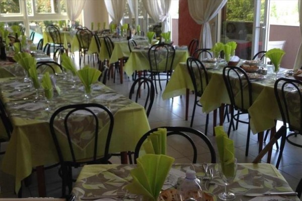 Restaurace s prostřenými stoly a zelenými ubrousky.