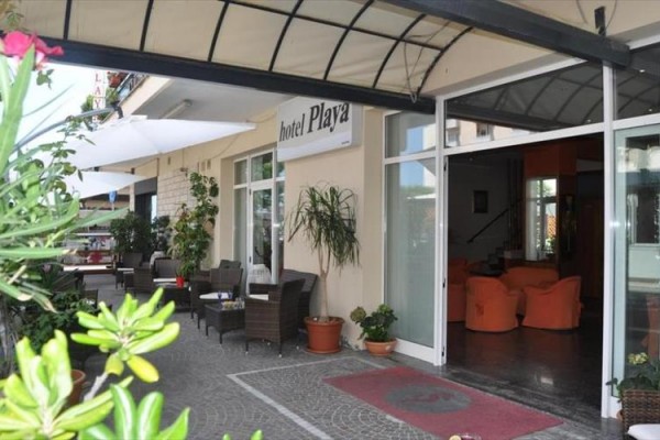 Vstup do hotelu s venkovní terasou a rostlinami.