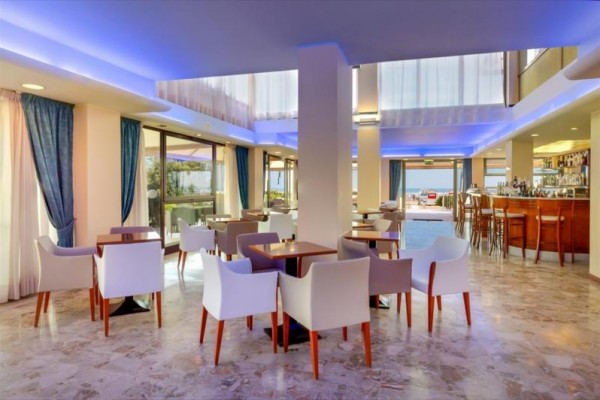 Moderní interiér restaurace s bílými křesly a modrým osvětlením.