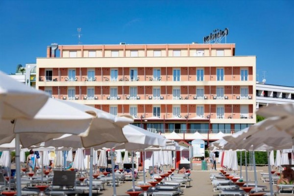 Hotel s balkóny a plážovými lehátky pod slunečníky.
