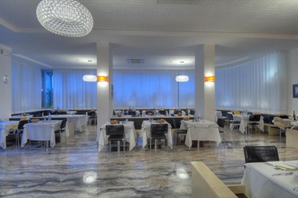 Moderní restaurace s bílými ubrusy a elegantním osvětlením.