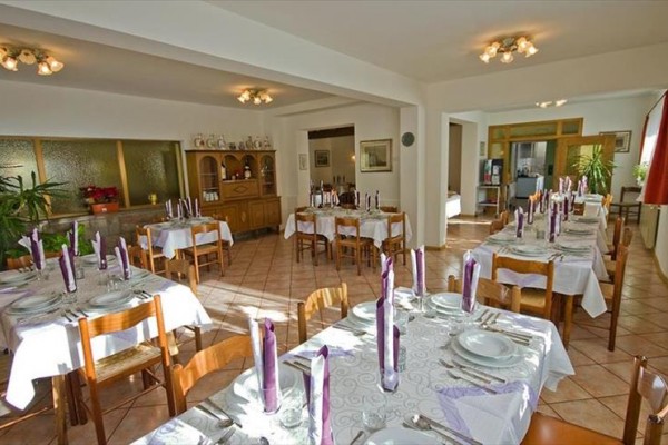 Restaurace s prostřenými stoly a fialovými svíčkami.