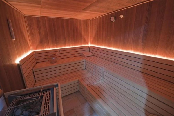 Dřevěná sauna s lavičkami a jemným osvětlením.  