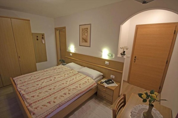 Ložnice s manželskou postelí, obrázkem na stěně a dřevěným nábytkem.