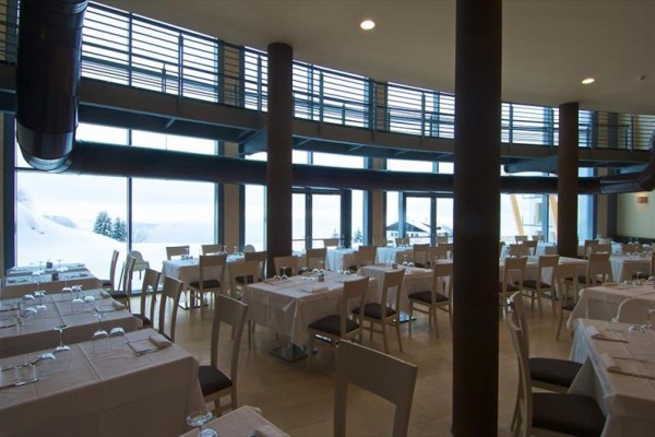 Prázdná restaurace s prosklenými stěnami a zasněženým výhledem.