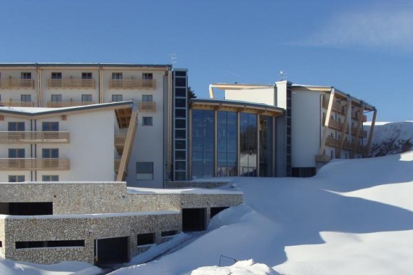 Moderní budova hotelu obklopená zasněženou krajinou.