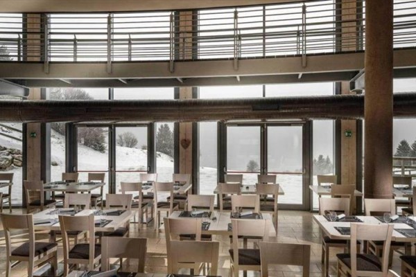 Restaurace s velkými okny a zasněženou krajinou venku.