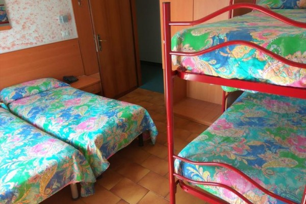 Pokoj s palandou a dvěma samostatnými postelemi s barevným povlečením.