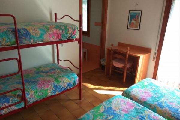 Pokoje s palandou a stolem, barevné povlečení.