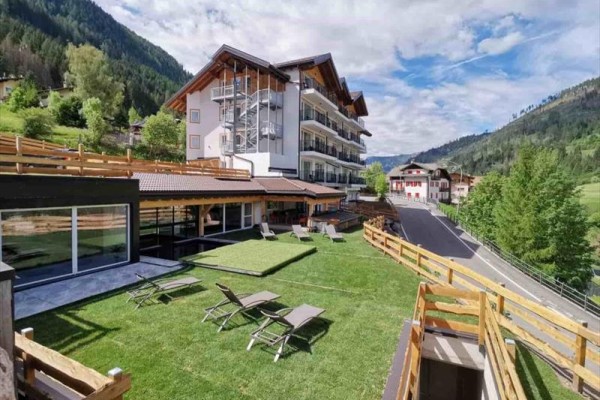 Hotel s rozlehlou zahradou a lehátky v horské krajině.