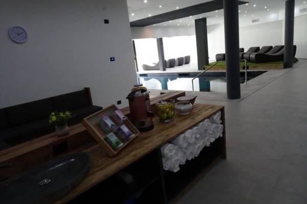 Interiér wellness centra s relaxačními lehátky a bazénem.