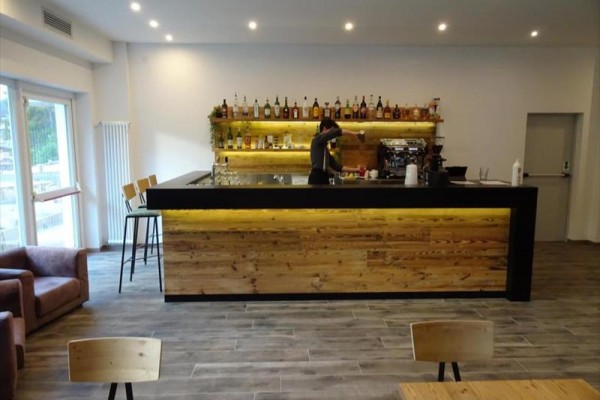 Moderní bar s dřevěným pultem, kde personál připravuje nápoj.