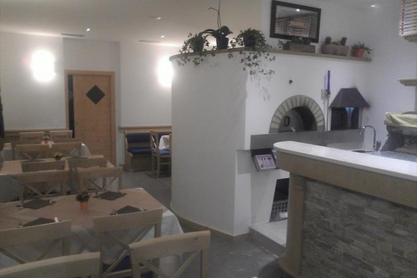 Restaurace s dřevěnými stoly a pecí na pizzu.  
