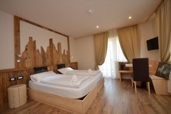 Dvoulůžkový pokoj v hotelu s dřevěným nábytkem a dekoracemi.  