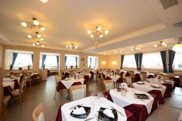 Elegantní interiér restaurace s prostřenými stoly a závěsy na oknech.