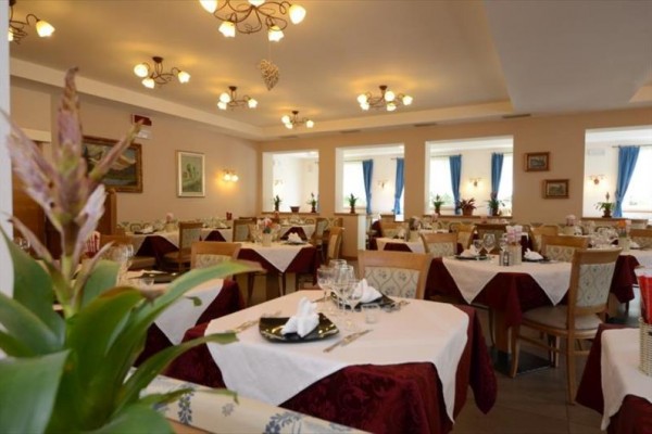 Elegantní restaurace s prostřenými stoly a dekoracemi v teplých barvách.