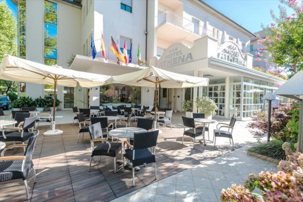 Venkovní posezení hotelu s deštníky a křesly.