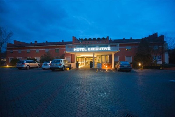 Vchod do hotelu Executive s parkovištěm za soumraku.