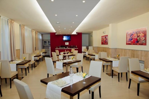 Moderní restaurace s bílými židlemi a prostřenými stoly.