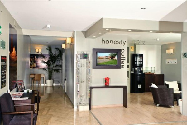 Moderní interiér kavárny s nápisem „honesty coffee“ na stěně.