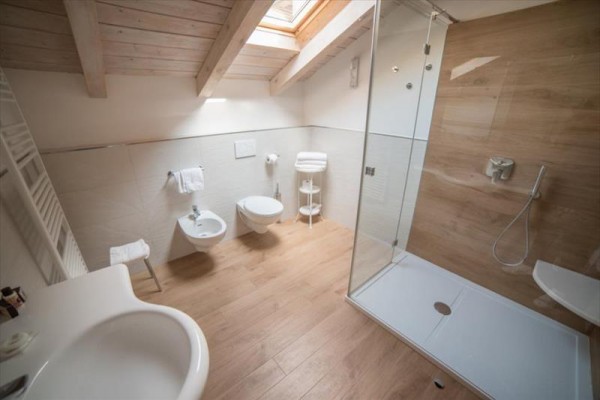 Moderní koupelna s dřevěnou podlahou, sprchovým koutem a střešním oknem.