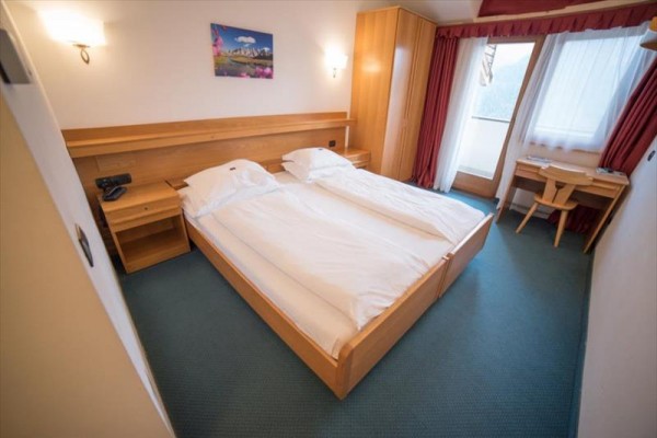 Dvojlůžkový pokoj s dřevěným nábytkem a balkónem.